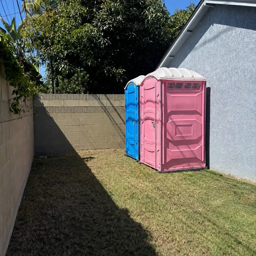 Pink and blue portable toilets in a backyard for a party