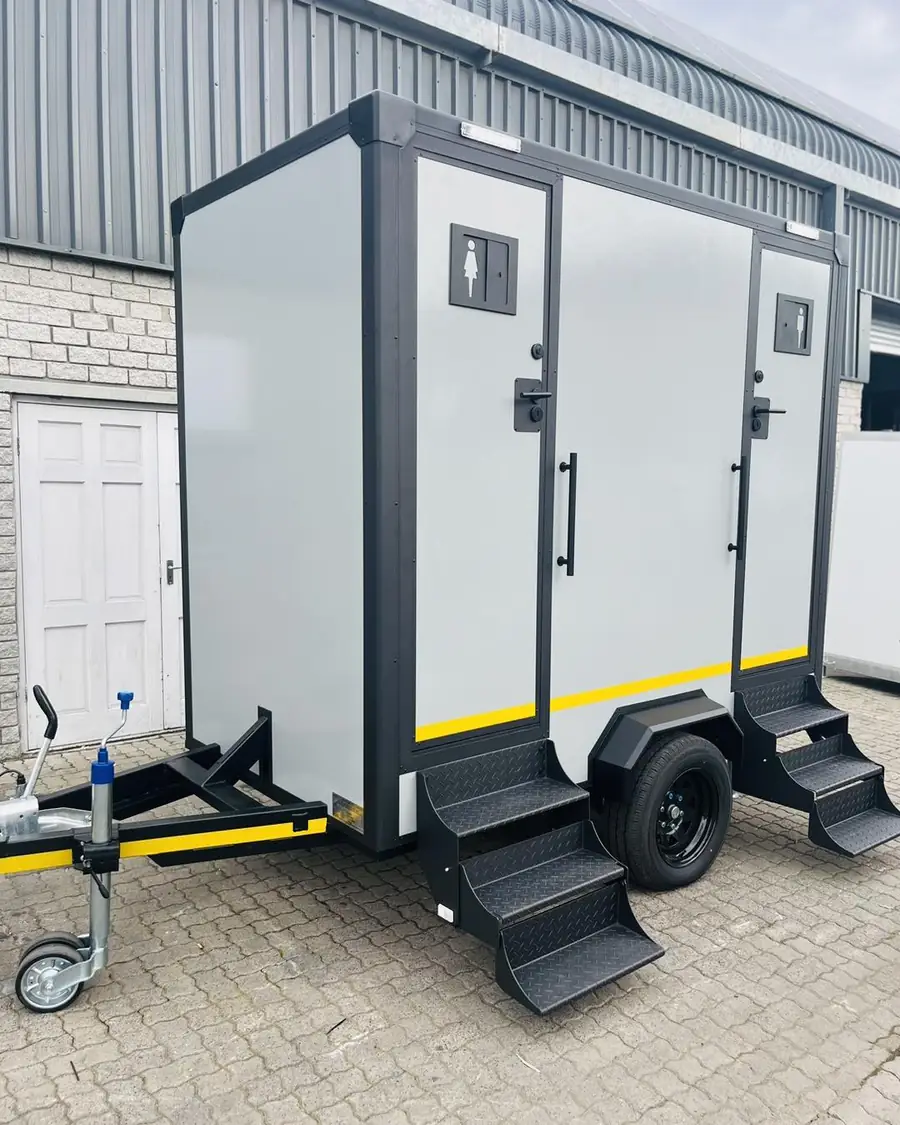 White two-door restroom trailer with steps on a paved lot