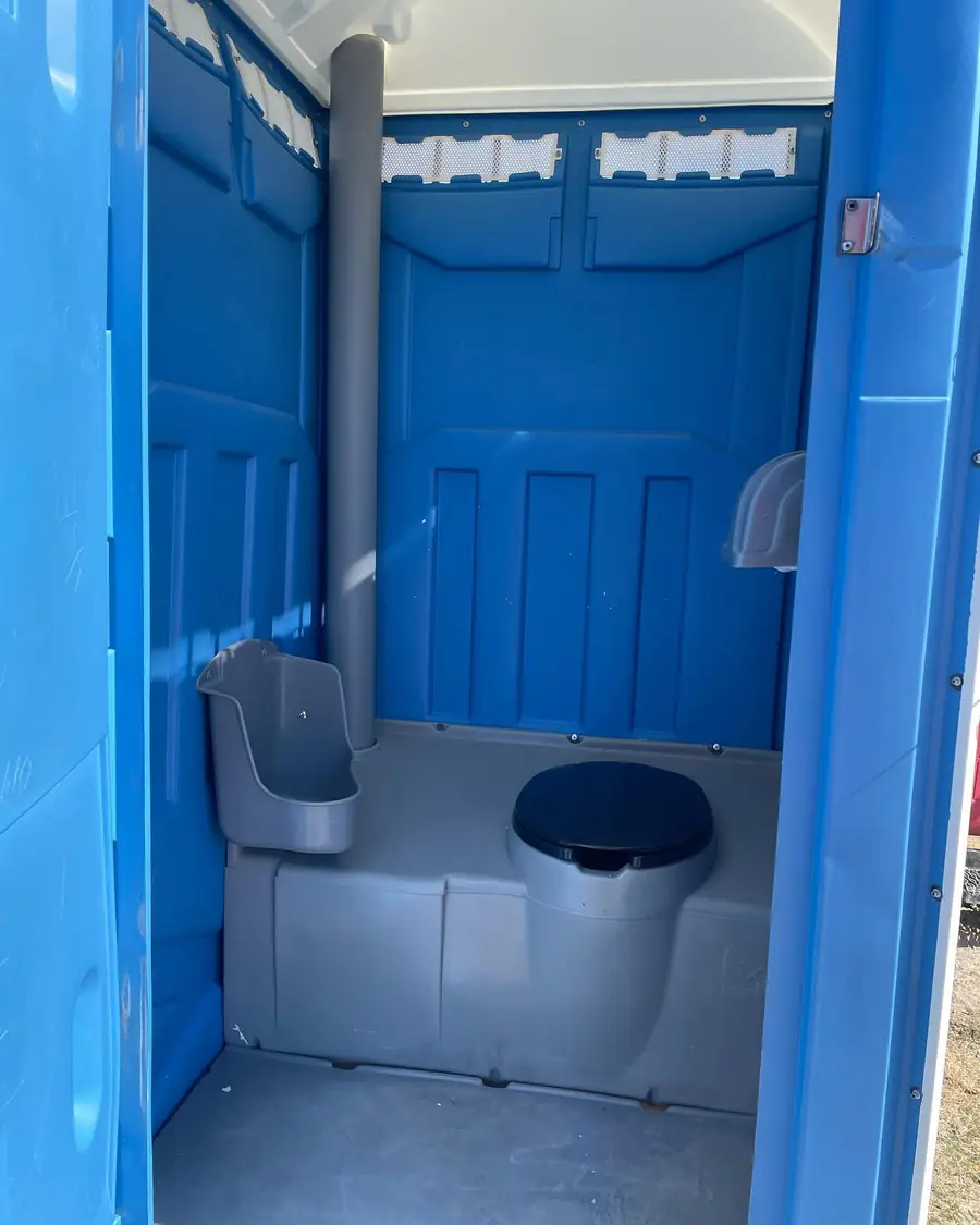 Inside a standard portable toilet showing urinal, seat and vent pipe