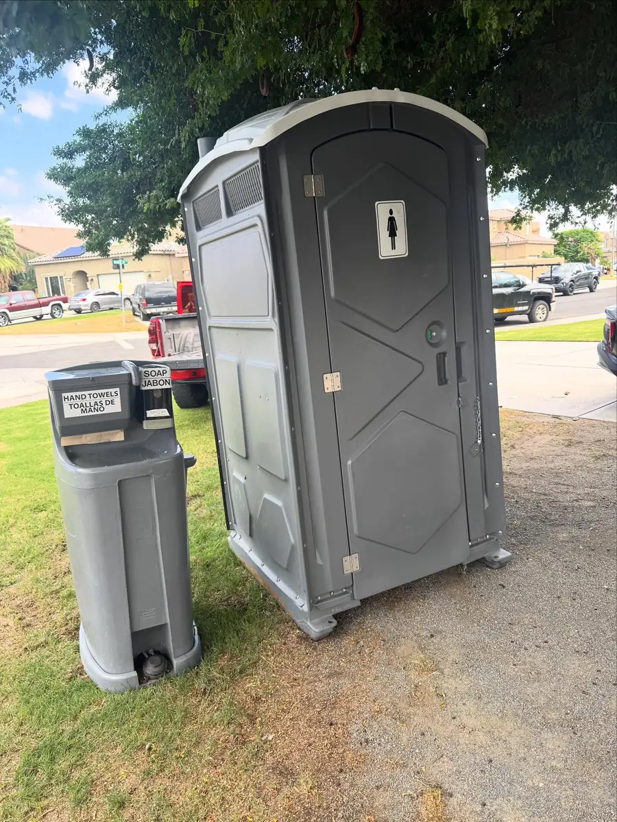 Portable toilet and hand wash station set on level grass